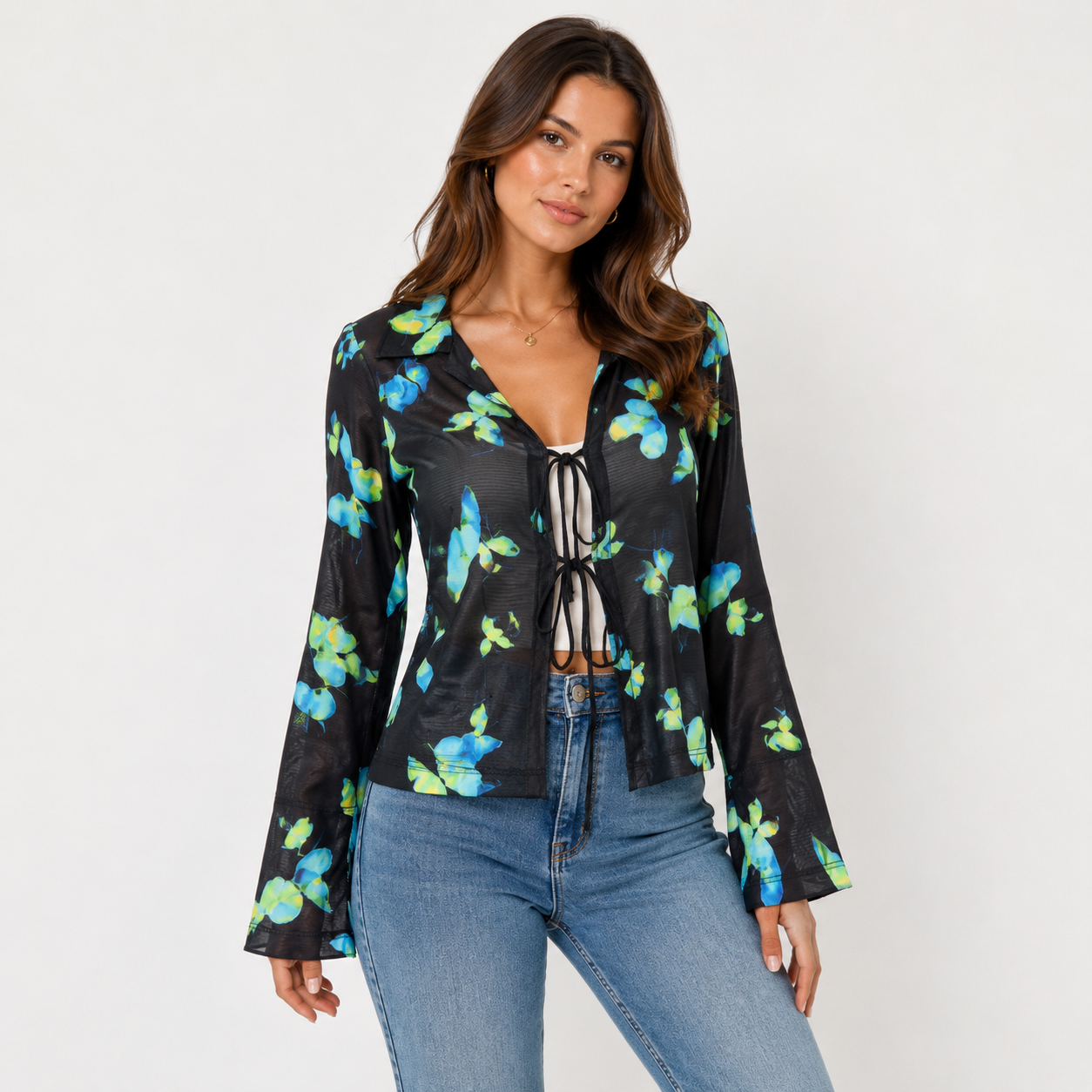 Woman wearing a black floral blouse and blue jeans on a white background