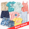 A collection of toddler summer clothing laid out on a white background, including beige shorts, a teal shark-print t-shirt, a mint striped polo, a coral floral dress, navy shorts, blue palm-print shorts, denim shorts, a pink striped t-shirt, a yellow butterfly-print t-shirt, and a light blue striped dress. A red diagonal banner reads 'Best Value'.